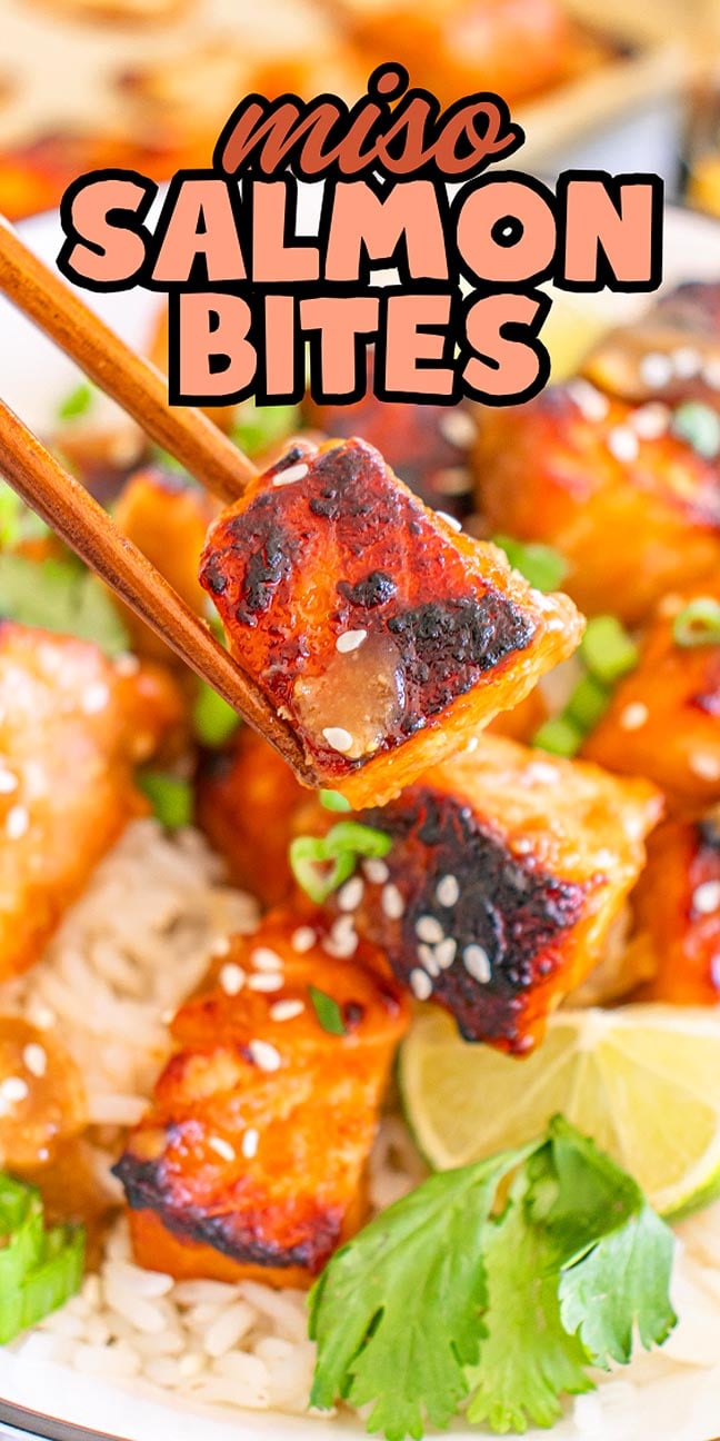 Chopsticks hold a glazed, seared miso salmon bite over rice, garnished with sesame seeds, lime, and cilantro.