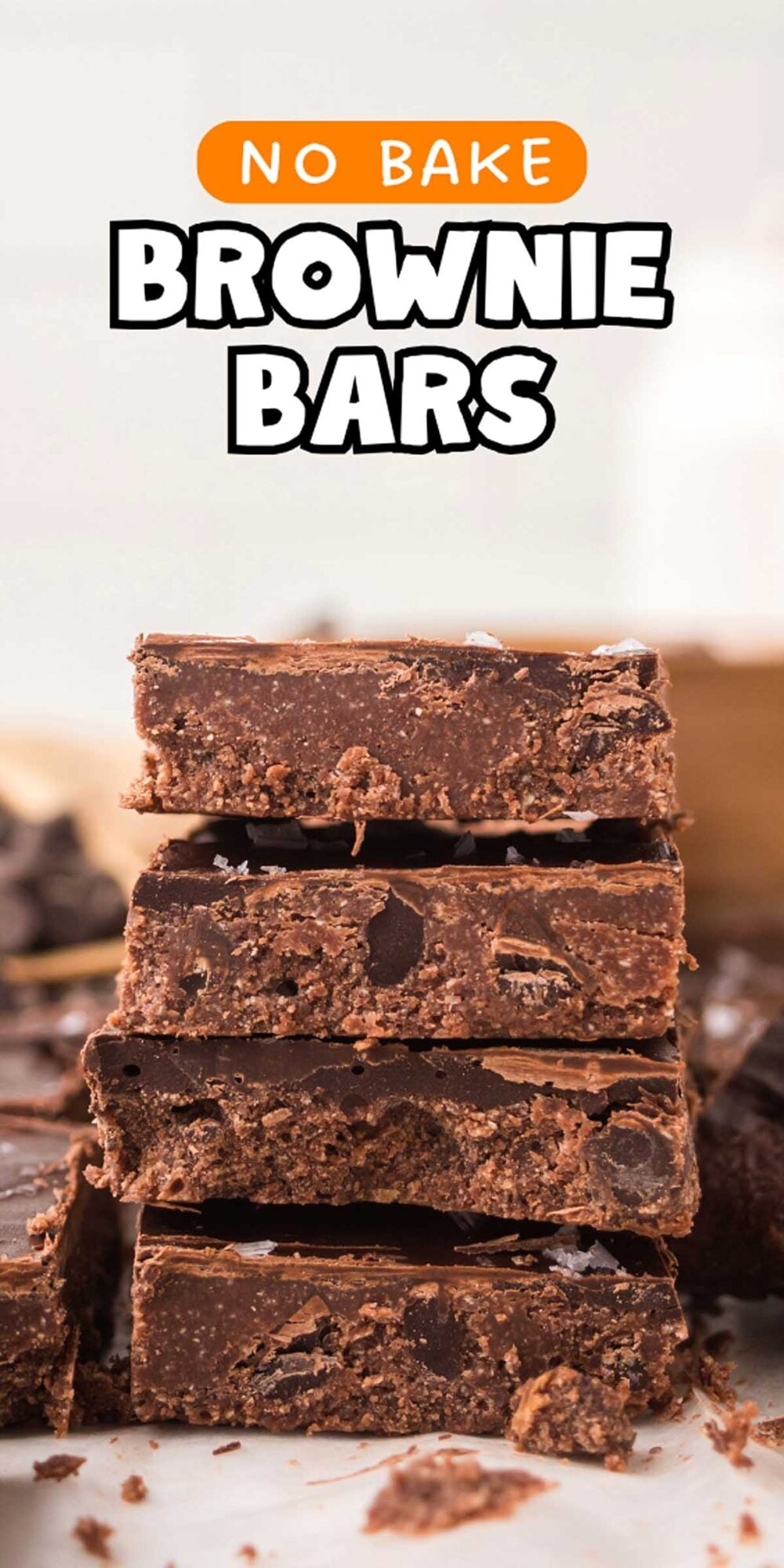A stack of four rich no bake brownie bars with chocolate chips, set on a countertop.