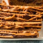 Slices of Peanut Butter Banana Bread drizzled with caramel icing, stacked on a white plate.