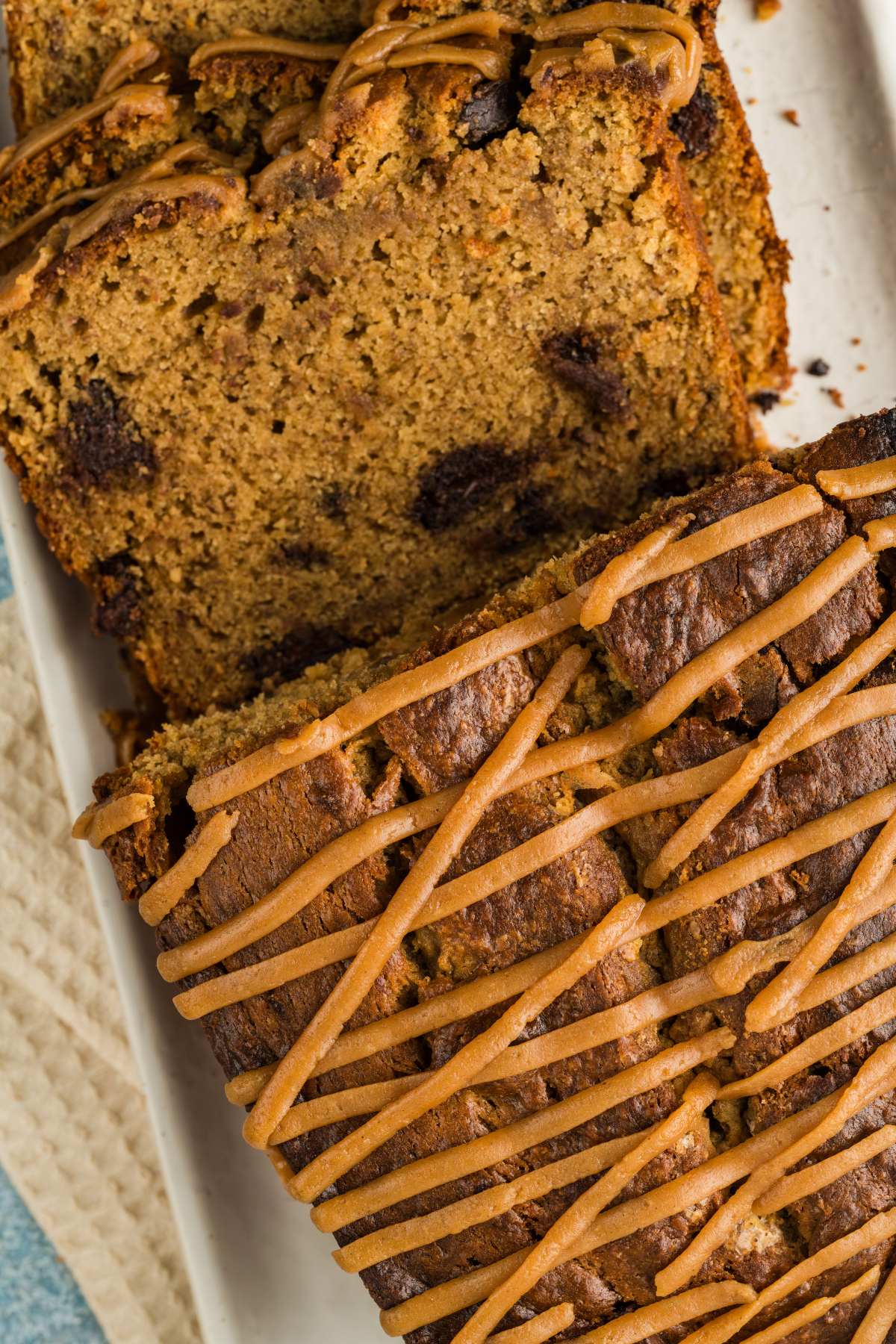Sliced loaf of banana bread with chocolate chips and a drizzle of icing on top.