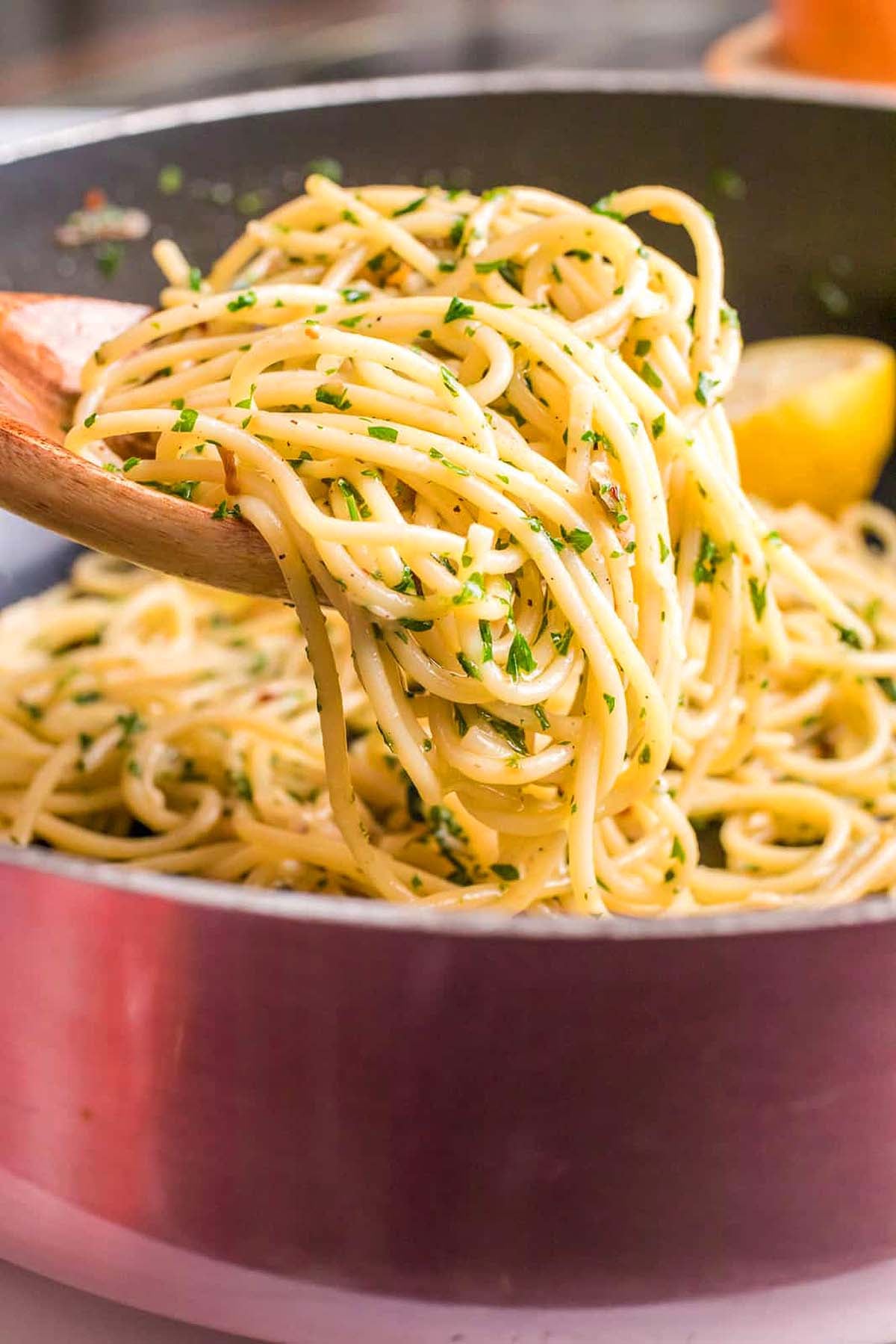 A wooden spoon lifts spaghetti with herbs from a pot, capturing the essence of classic Italian pasta recipes.