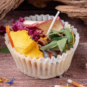 A white wrapper holds homemade fire starters with dried flowers, leaves, and herbs on a rustic wooden surface.