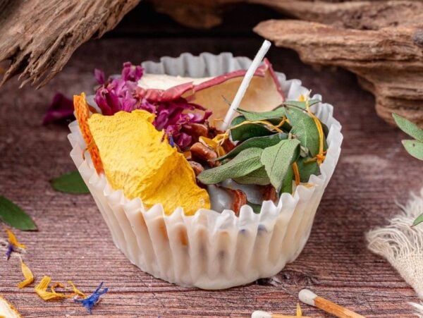 A white wrapper holds homemade fire starters with dried flowers, leaves, and herbs on a rustic wooden surface.