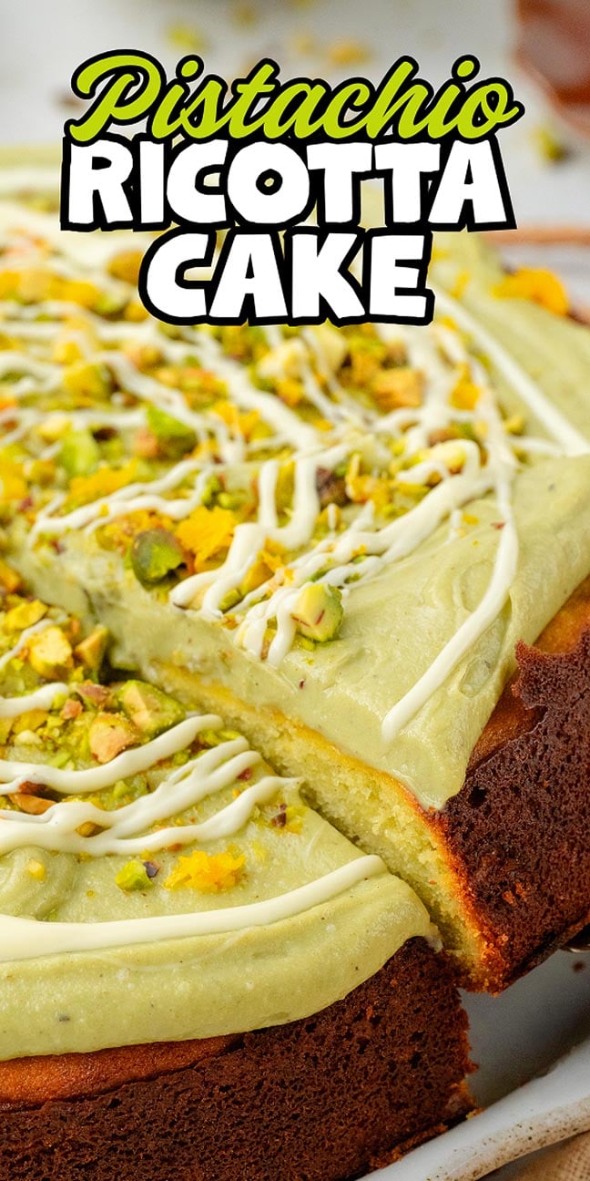 Close-up of a pistachio ricotta cake with green frosting, chopped pistachios, and a white drizzle on top.