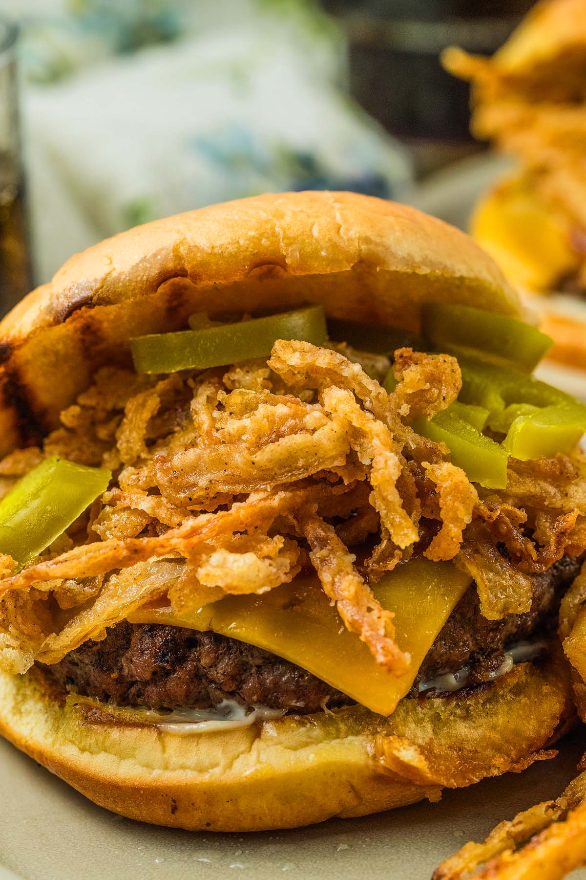 A cowboy burger topped with fried onions and pickles on a toasted bun, close-up view.