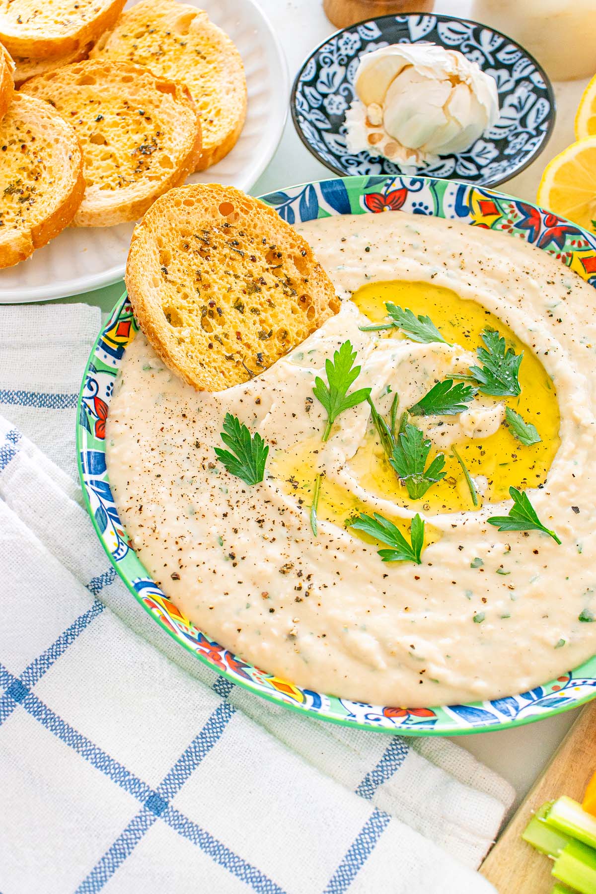 Creamy white bean dip topped with olive oil, parsley, and pepper, served with toasted bread slices.