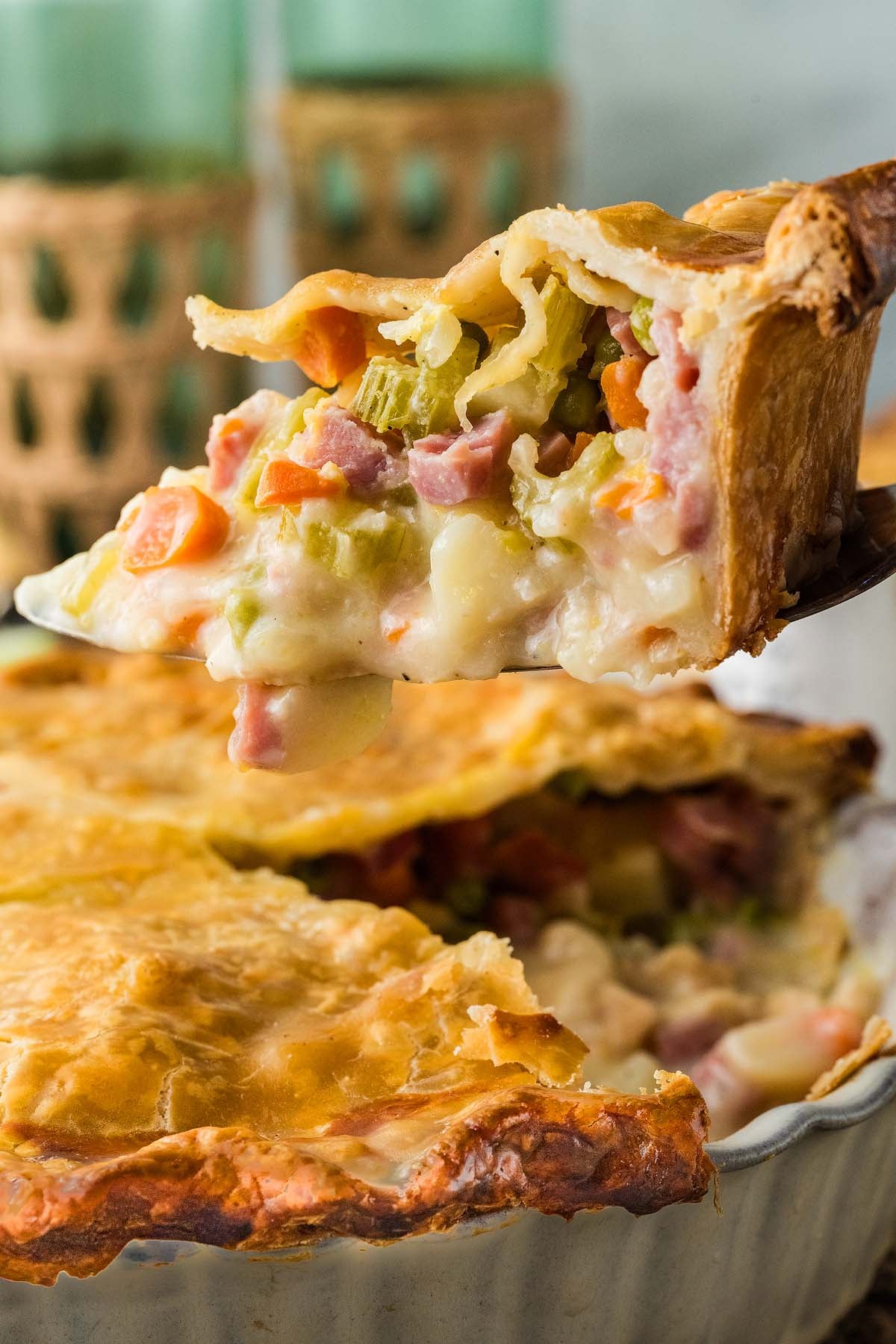 A slice of ham and vegetable pot pie being lifted from a baking dish.