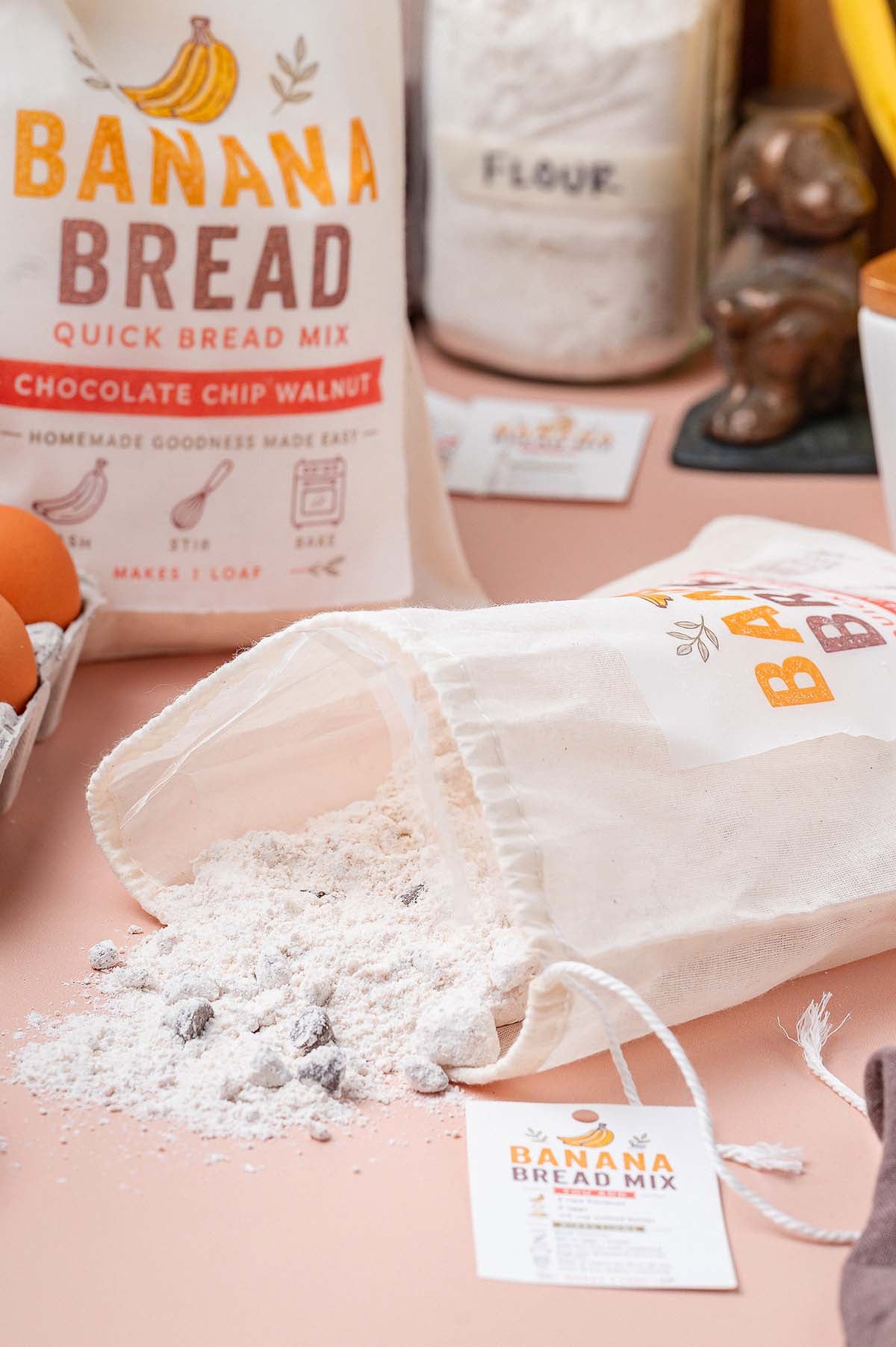A fabric pouch of banana bread mix open on a table, with dry mix spilling out.