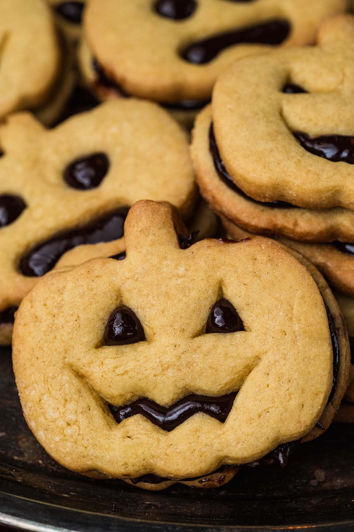 Jack-o’-lantern shaped sandwich cookies filled with dark chocolate.