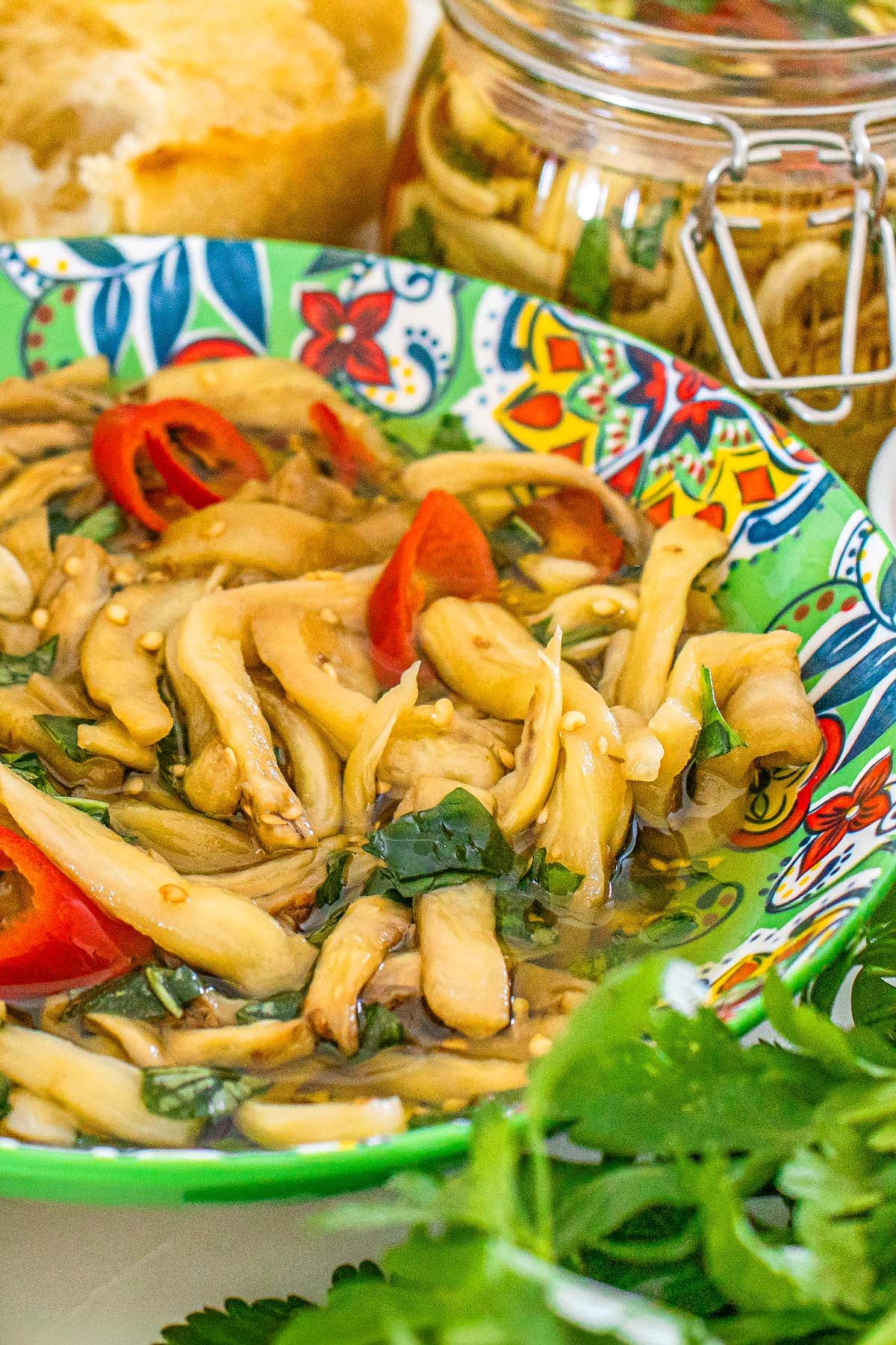 Pickled eggplant with red peppers and herbs in a patterned bowl.