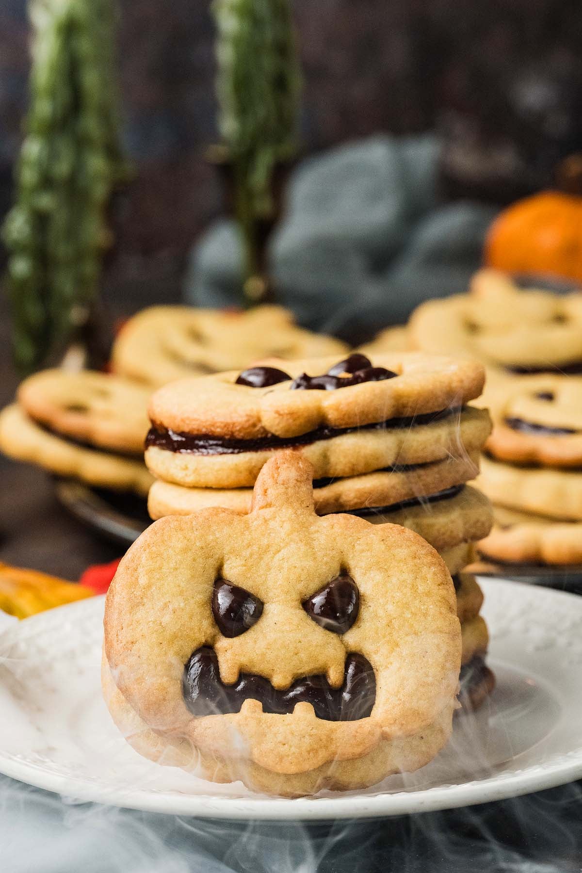 A stack of pumpkin-shaped sandwich cookies filled with chocolate.