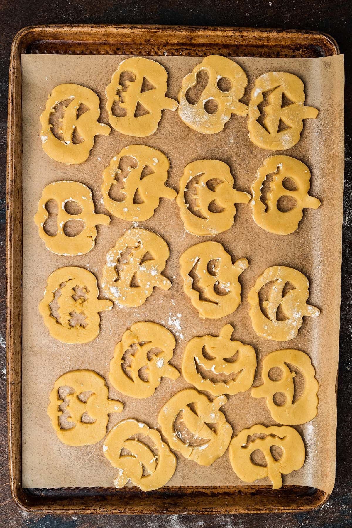 Unbaked jack-o-lantern shaped sugar cookies on a baking sheet.