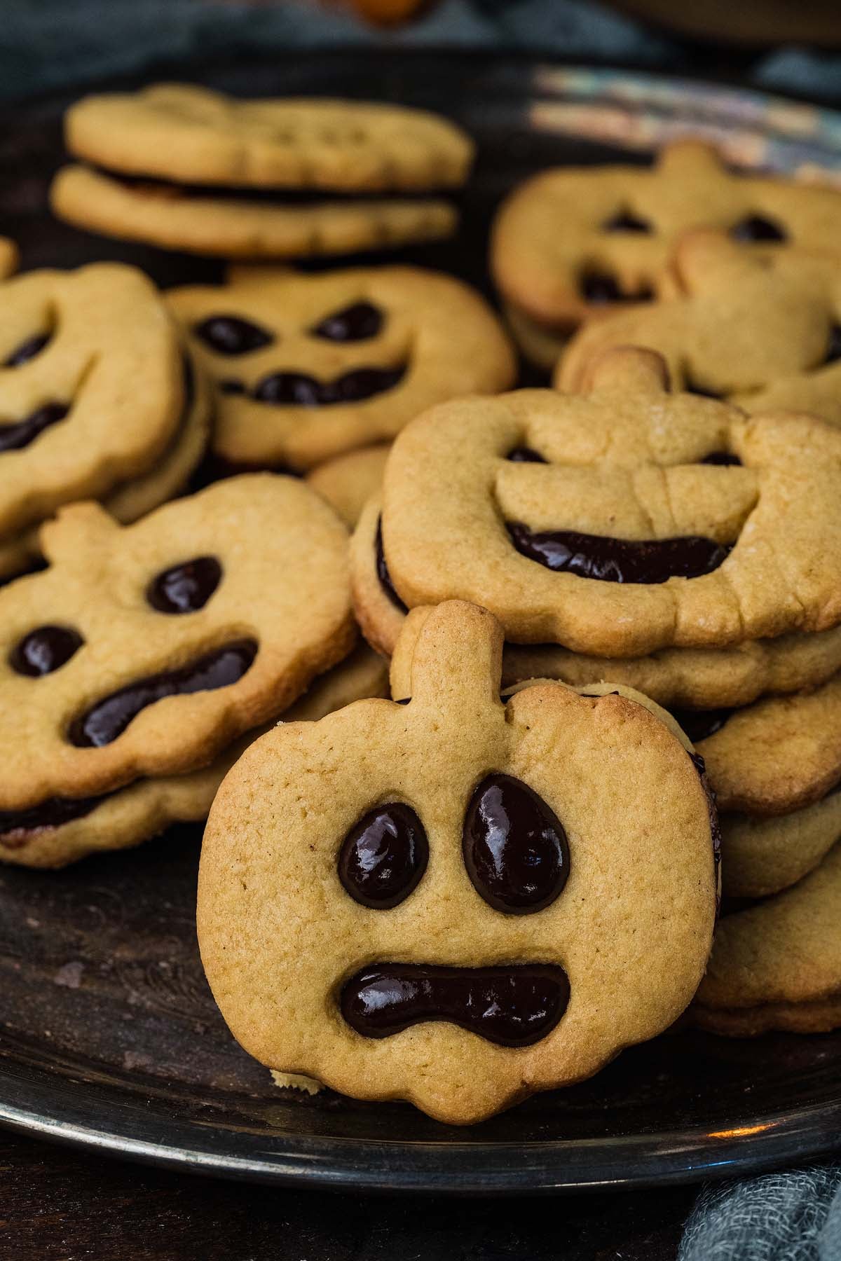 Pumpkin-shaped sandwich cookies with chocolate filling and jack-o’-lantern faces.