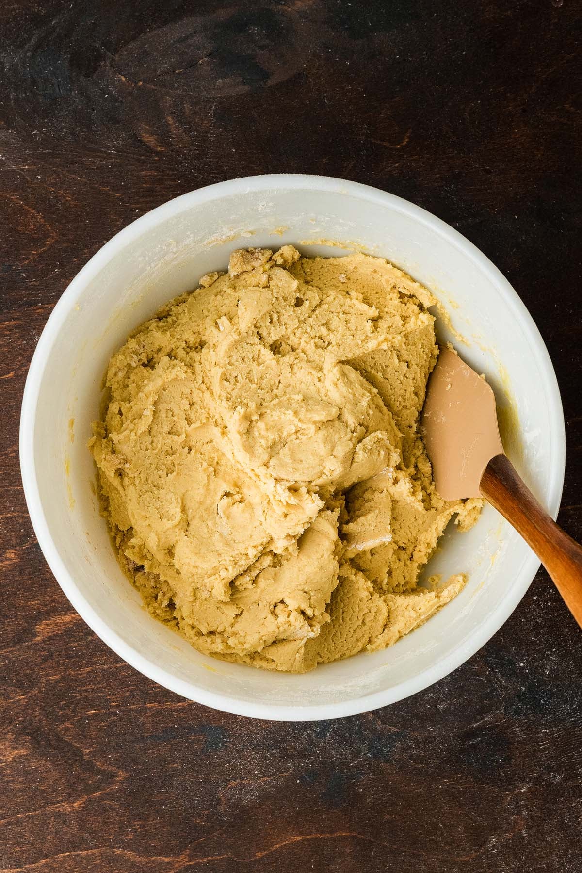 Cookie dough in a white mixing bowl with a silicone spatula.