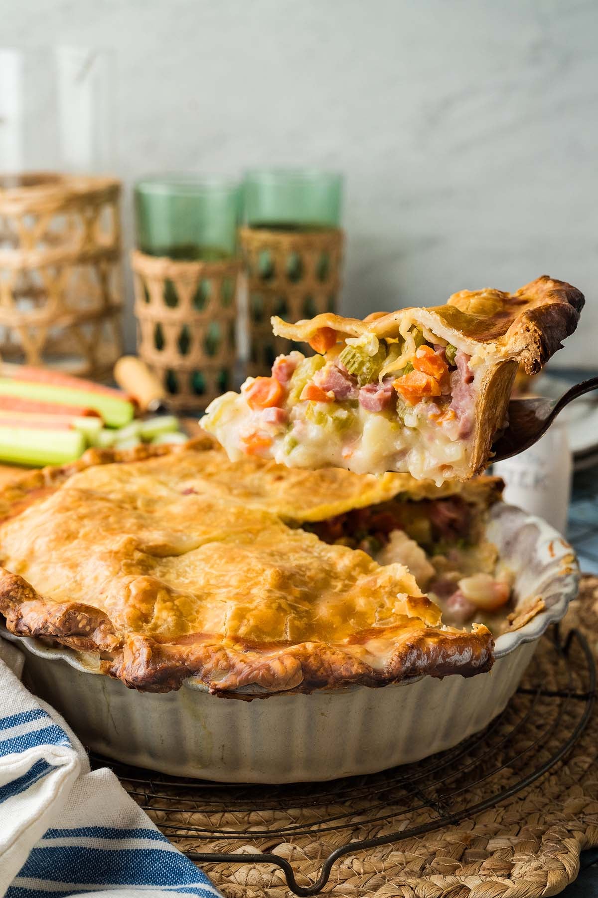 A slice of ham and vegetable pot pie being lifted from a golden-crusted pie.