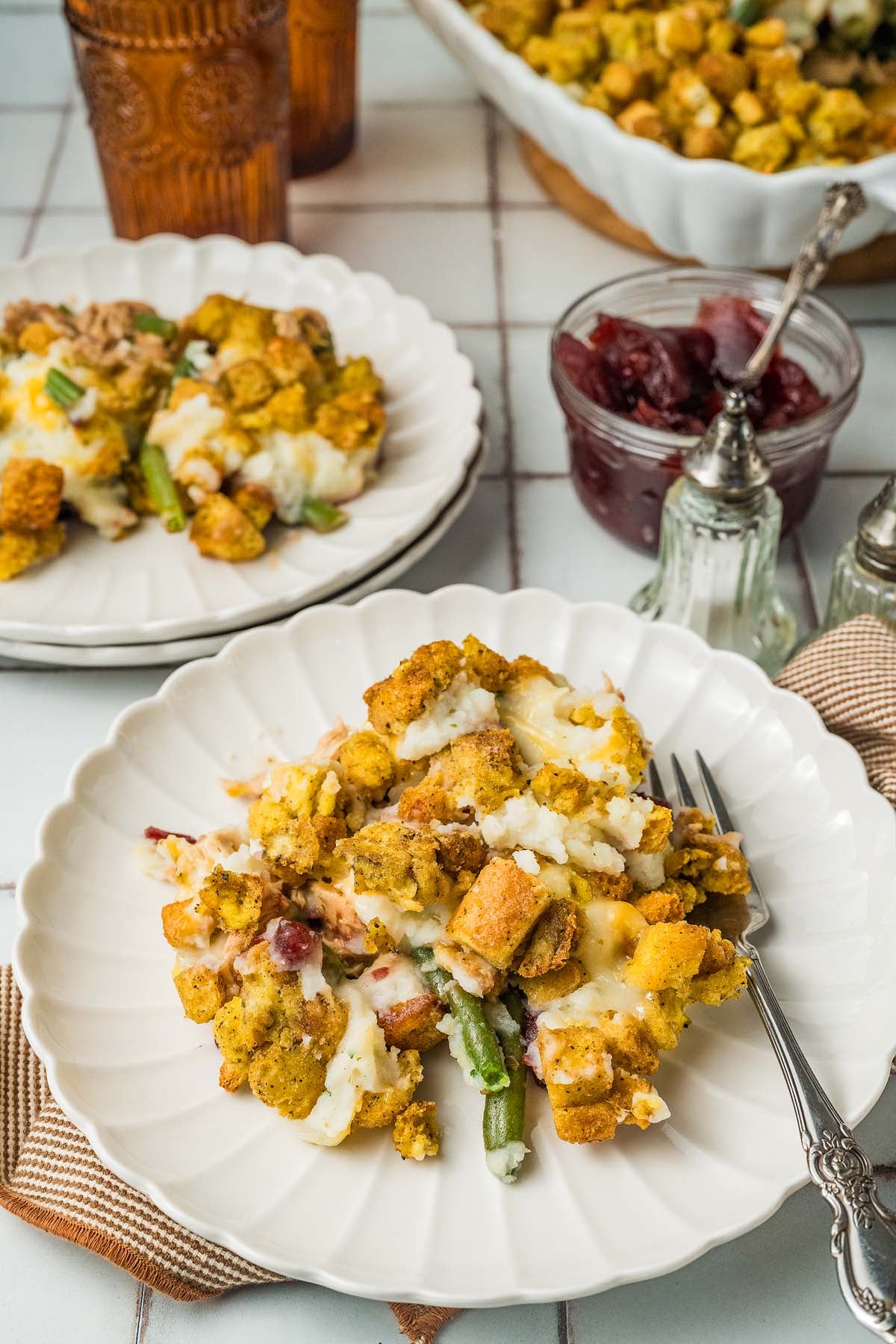 A plate serving a Thanksgiving leftovers casserole with stuffing, green beans, and melted cheese.