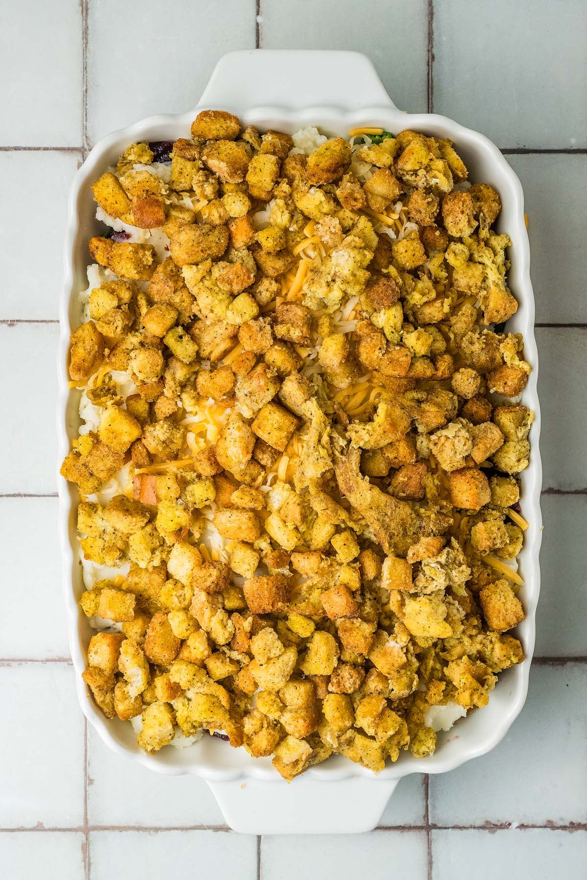 Casserole in a white dish topped with a layer of leftover thanksgiving stuffing.