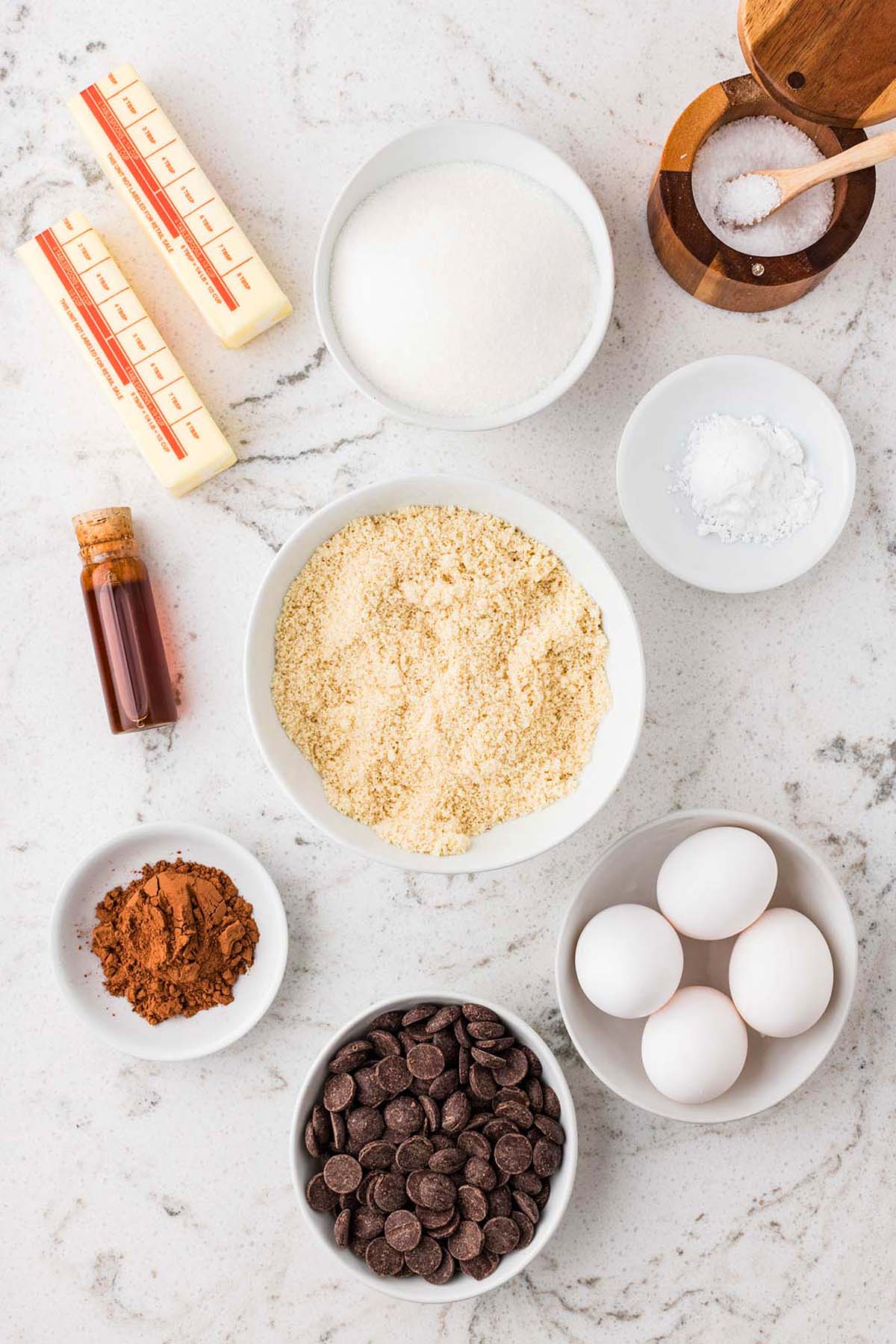 Ingredients for baking, including butter, sugar, almond flour, cocoa powder, chocolate chips, and eggs.
