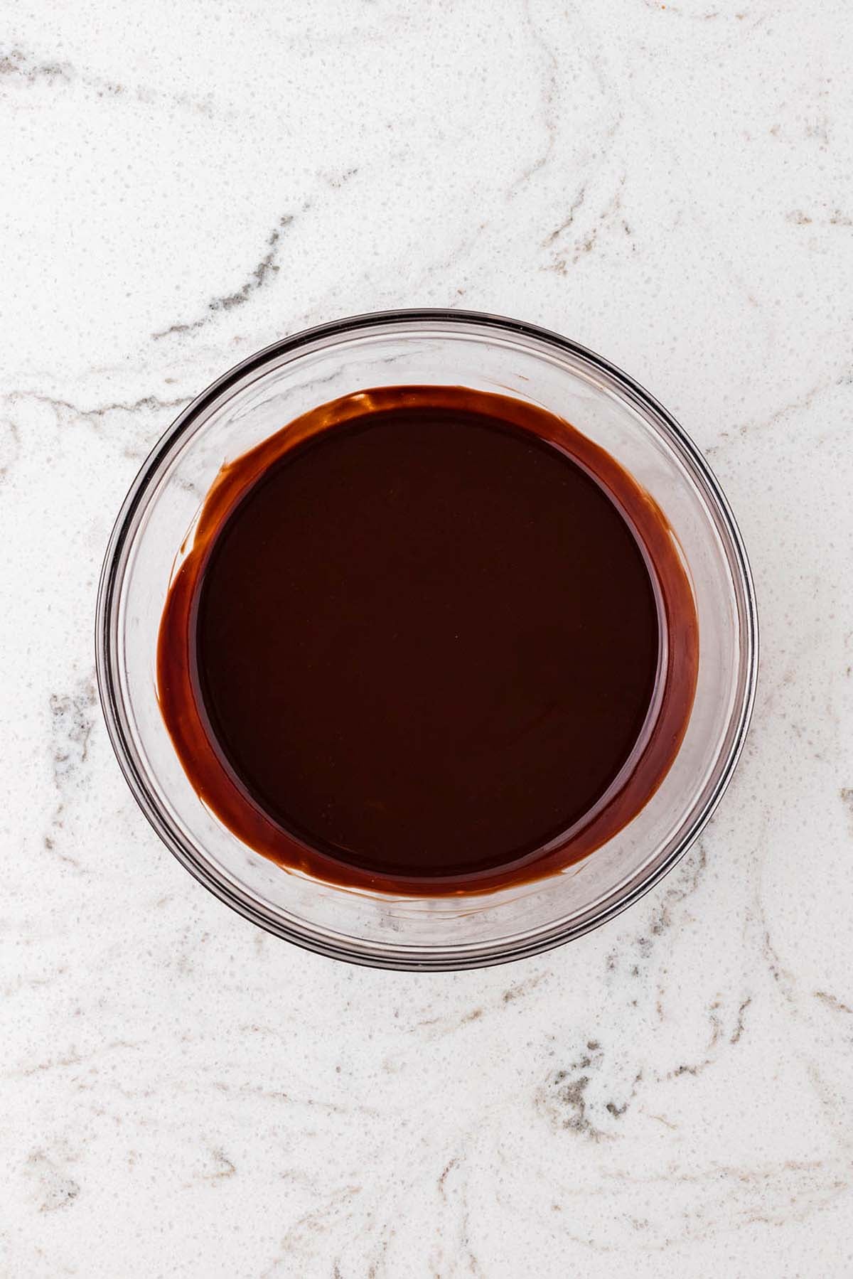 A glass bowl of melted dark chocolate.