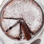 A round Italian chocolate torta caprese cake dusted with powdered sugar.