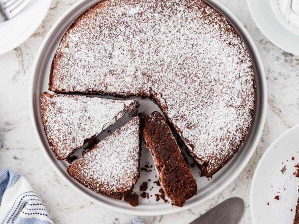 A round Italian chocolate torta caprese cake dusted with powdered sugar.